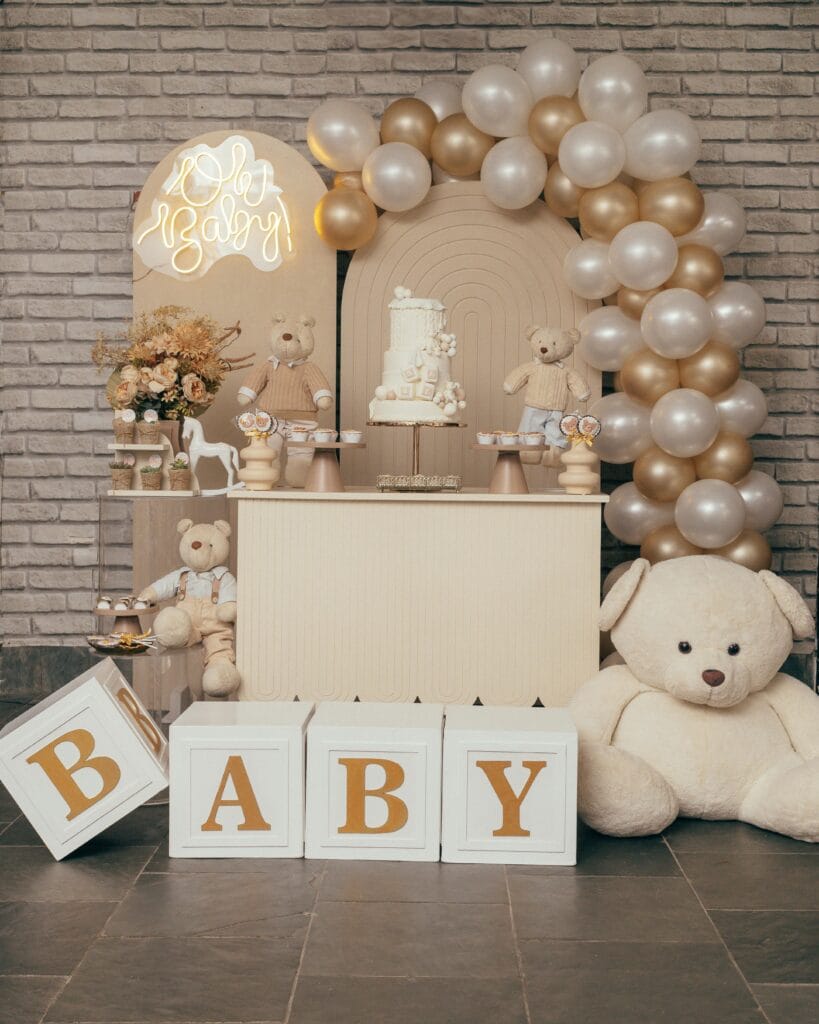 Charming baby shower setup with teddy bears, balloons, and elegant decor in soft tones.