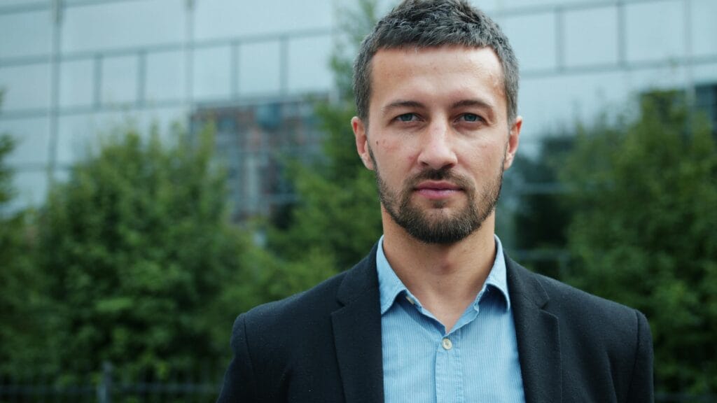 Confident man in business attire standing outside a modern building.
